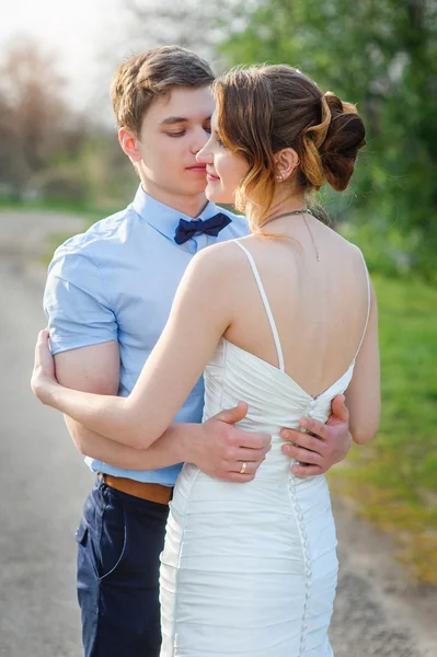 Loving bride and groom embrace on the road in park — Stock Photo, Image