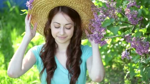 Bella giovane donna con cappello di paglia e seduta nel parco — Video Stock