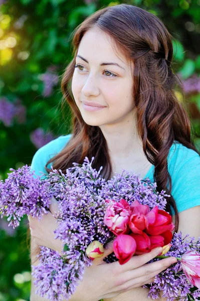 Schöne Frau mit einem Strauß Tulpen und Flieder — Stockfoto