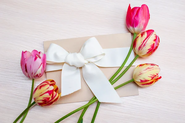 Caja de regalo festiva con flores frescas de tulipán sobre fondo blanco — Foto de Stock