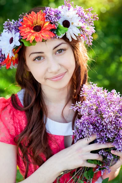 Krásná mladá žena s věncem květů v jarní zahradě — Stock fotografie