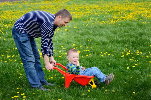 Padre caminando con su hijo en una floreciente pradera de primavera — Foto de Stock