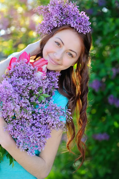 Schöne Mädchen mit einem Strauß Flieder zu Fuß im Frühling Park — Stockfoto