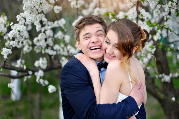 Bruden och brudgummen gå i blommande våren trädgård — Stockfoto