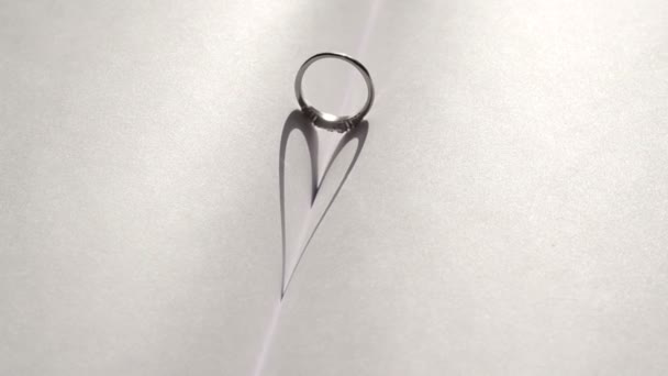 Anillo de boda que proyecta una sombra en forma de corazón en el libro — Vídeo de stock