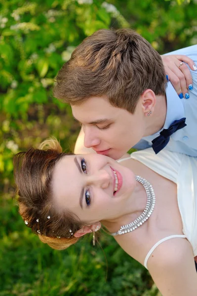 El novio feliz besa a la novia en la mejilla. Paseo de primavera — Foto de Stock