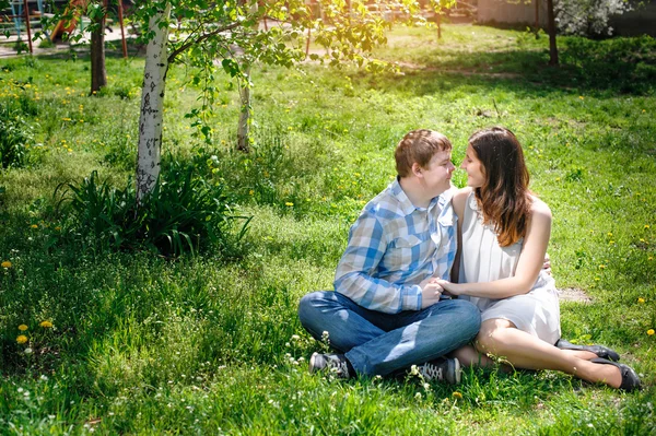 恩爱夫妻坐在草地上，在春天阳光灿烂的日子 — 图库照片