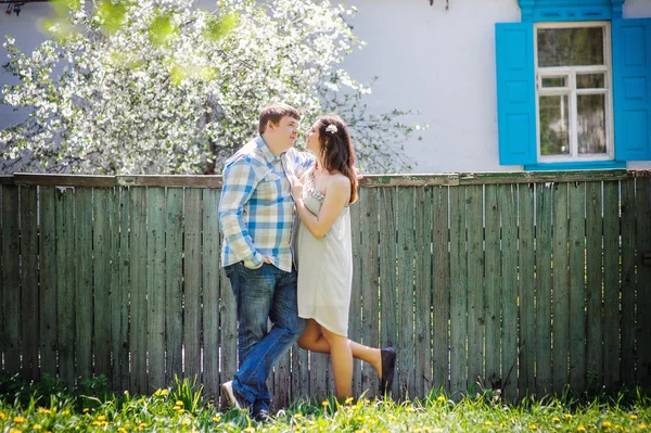 Loving couple standing near fence in the spring sunny day — Stock Photo, Image