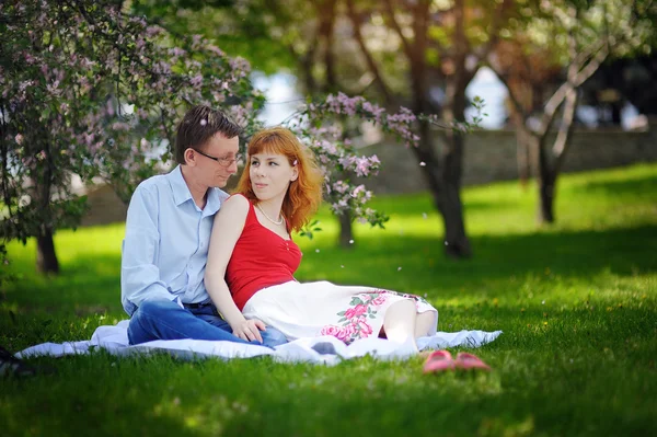 Joven pareja amorosa sentada en el parque en la hierba en primavera — Foto de Stock