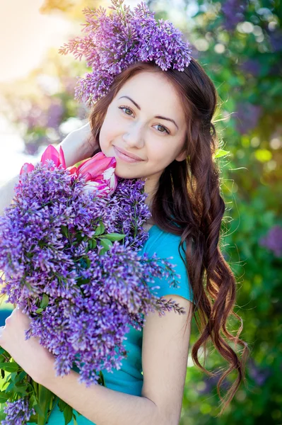 Vacker flicka med en bukett av lila i händer promenader på våren park — Stockfoto