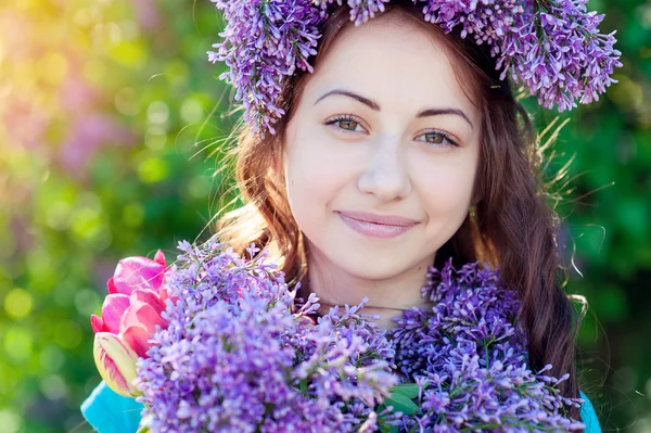 Hermosa chica con un ramo de lila en las manos caminando en el parque de primavera —  Fotos de Stock