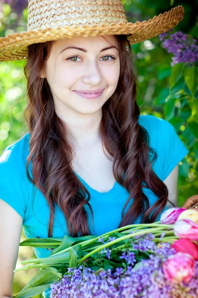 Mulher bonita em chapéu de palha com um buquê de flores — Fotografia de Stock