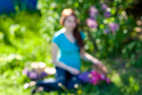 漂亮的女孩坐在一束淡紫色的春天公园草地上 — 图库照片