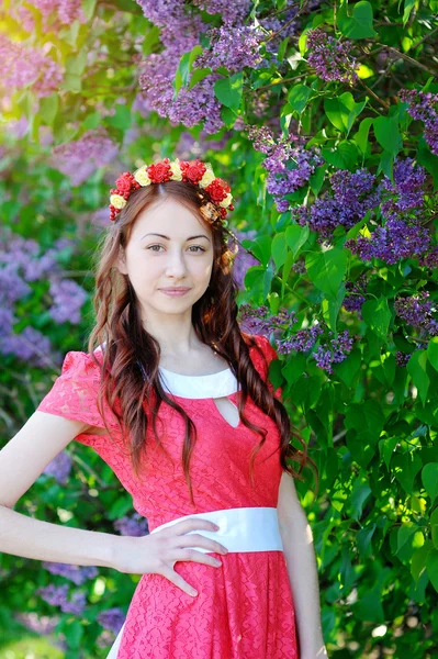 Menina bonita em um vestido vermelho em um fundo lilás — Fotografia de Stock