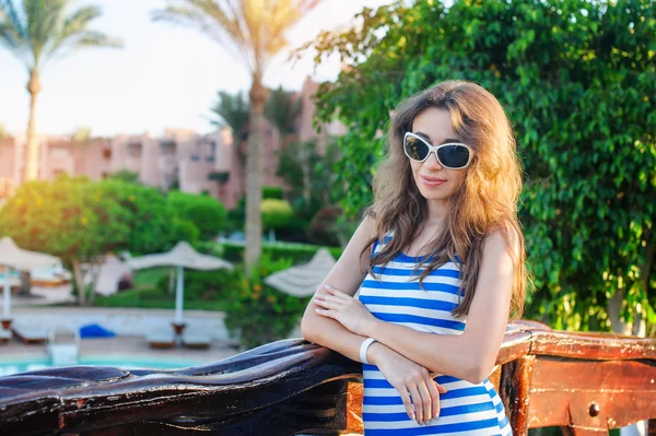 Beautiful woman in a striped dress walks in the summer park — Stock Photo, Image