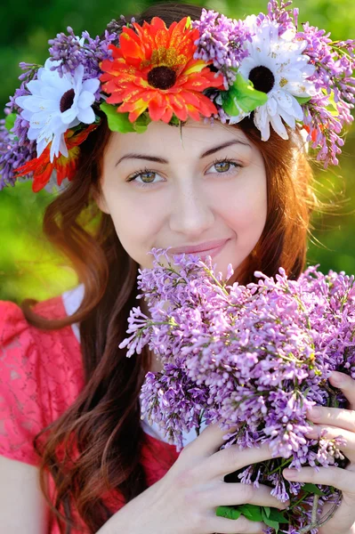 Schöne Frau mit einem Kranz und einem Strauß Flieder — Stockfoto