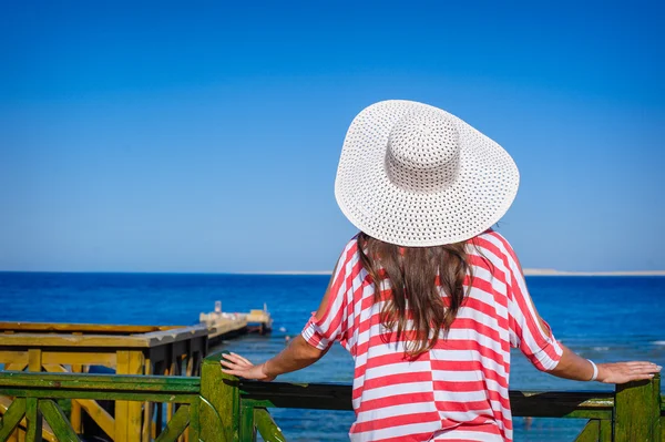 Woman in a big white hat looks at sea — Stock Photo, Image