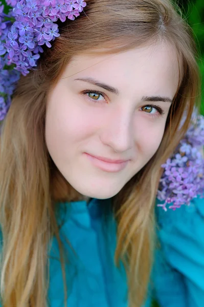 Mulher bonita com uma coroa de flores de cor lilás caminha no parque — Fotografia de Stock