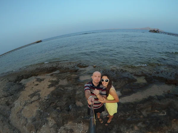 Счастливая, молодая пара делает селфи на пляже — стоковое фото