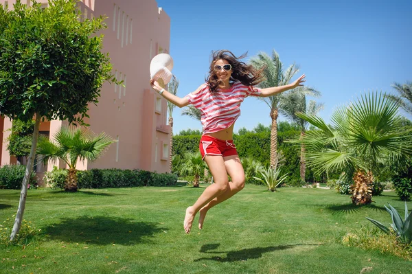 Feliz joven mujer saltando sobre la hierba en reposo — Foto de Stock