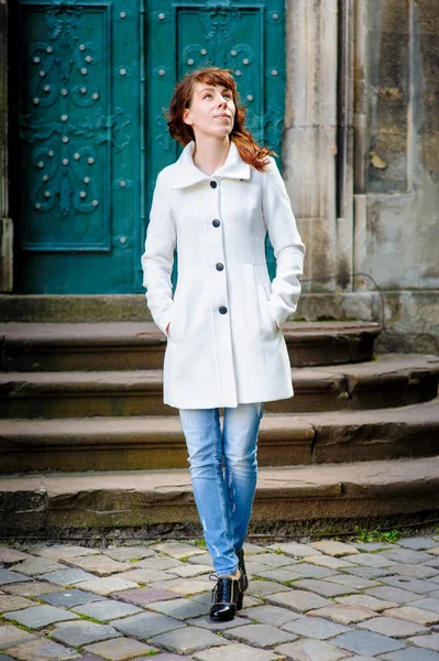 Young woman in a white coat walking through the old Lviv — Stock Photo, Image