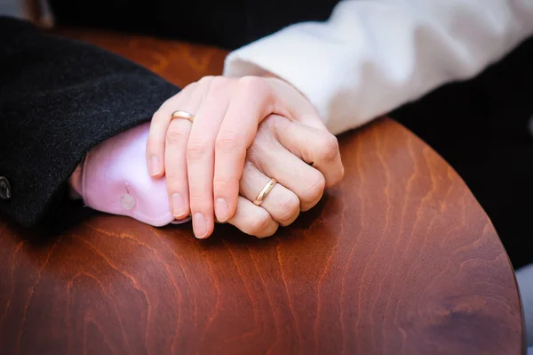 Bruid bezit van de bruidegom hand op de tafel — Stockfoto