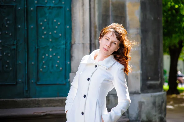 Young woman in a white coat walking through the old Lviv — Stock Photo, Image