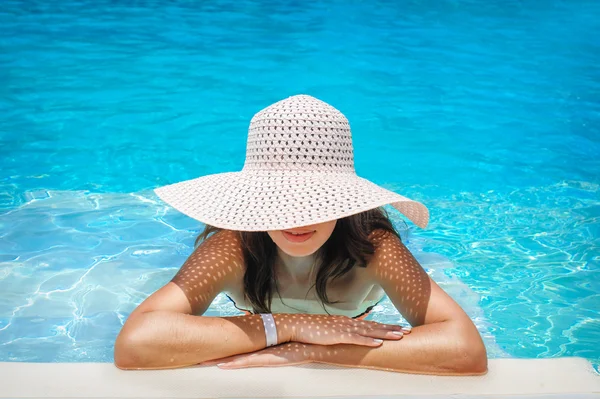Jovem mulher de chapéu branco descansando na piscina — Fotografia de Stock