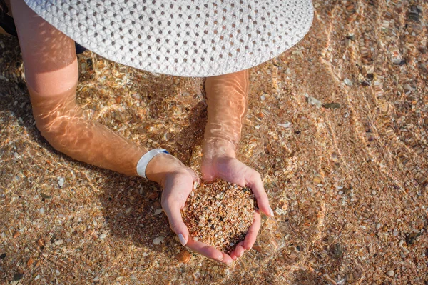 Sand i kvinnliga händer i vatten på nära håll — Stockfoto