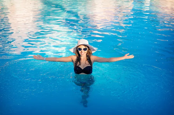 수영장에 떠 있는 모자와 행복 한 여자 — 스톡 사진