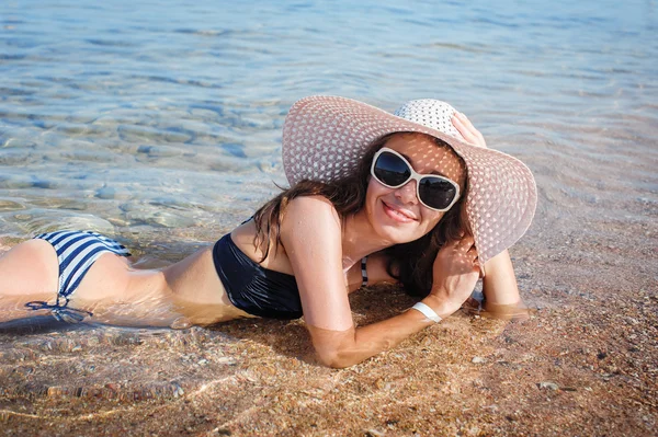 A fehér kalapot, hanyatt fekszik a tenger gyönyörű nő — Stock Fotó