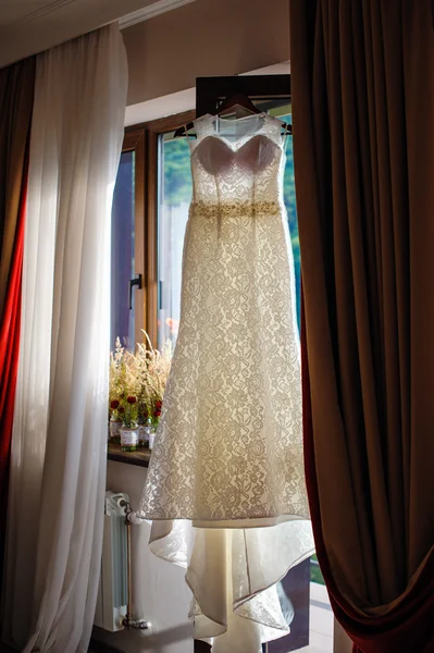 Белое платье невесты висит перед окном — стоковое фото
