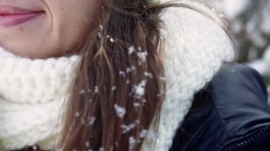 young woman in a white hat and a scarf and snow on her hair