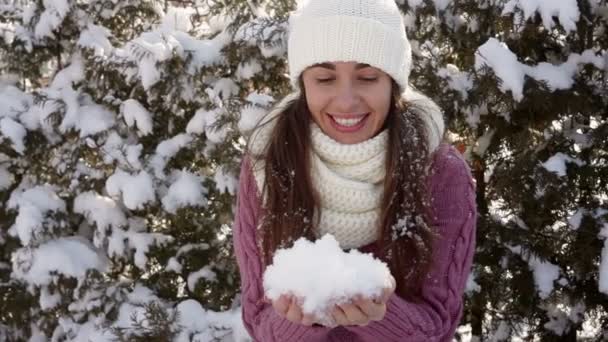 Mujer joven con un sombrero blanco sosteniendo la nieve — Vídeo de stock