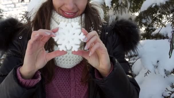 Jovem mulher em um chapéu branco segurando um floco de neve decorativo — Vídeo de Stock