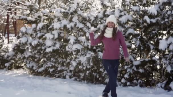 Jonge vrouw in een witte hoed gooien sneeuwballen — Stockvideo