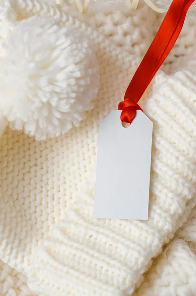 Capuchon et étiquette en tricot blanc avec ruban rouge — Photo