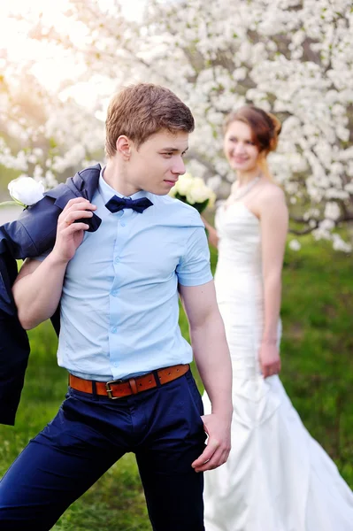 Bride and groom walking in the blossoming spring garden — Stock Photo, Image