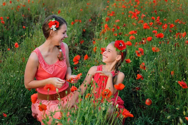 Haşhaş alan üzerinde Kırmızı elbiseli iki kız — Stok fotoğraf