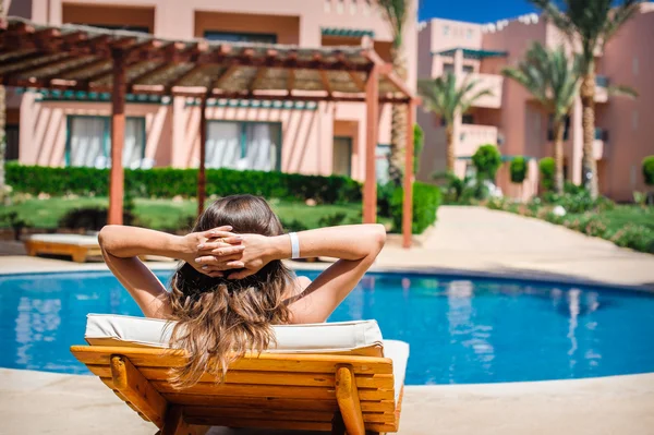 Frau liegt auf einer Liege am Pool des Hotels — Stockfoto