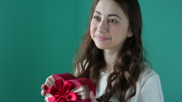 Belle jeune femme souriante avec un cadeau en forme de cœur dans ses mains — Video