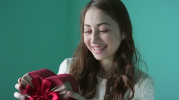 Hermosa joven sonriente mujer con un regalo en forma de corazón en sus manos — Vídeos de Stock