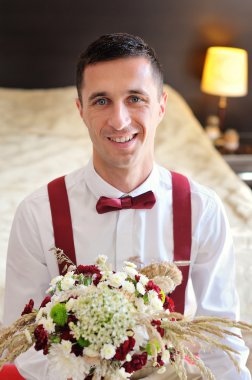 happy groom holding a bouquet