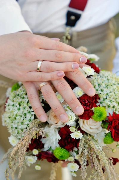 Hands of the bride and groom on bouquet — Stock Photo, Image