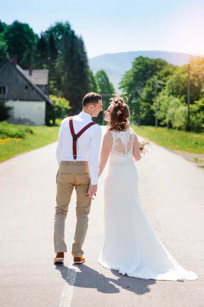 Bride and groom walking on the road — Stock Photo, Image