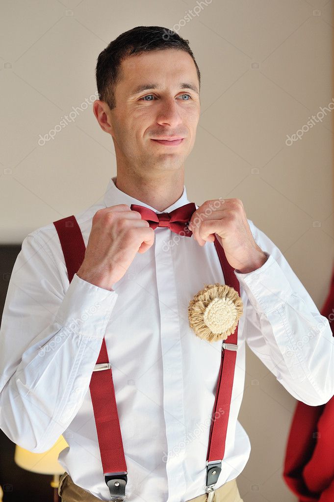 groom wears a red tie on a white shirt