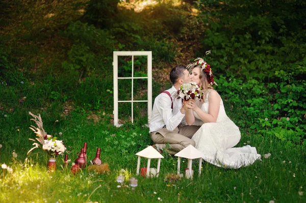 Novia y novio sentado en un parque en la hierba — Foto de Stock