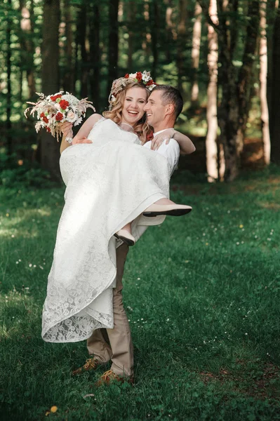 Feliz novio sostiene a su novia en sus brazos — Foto de Stock