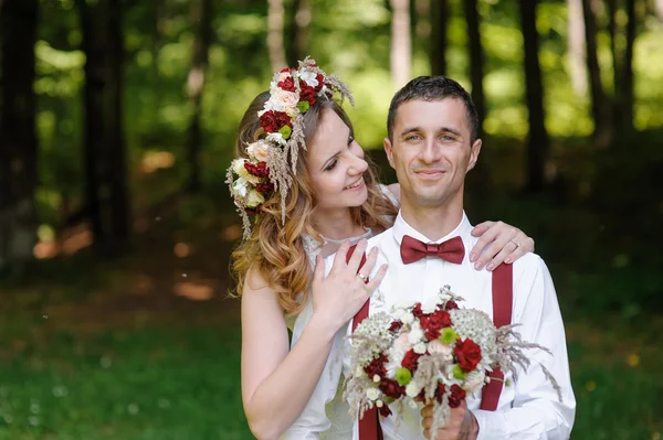 Happy bride and groom walking in the summer forest — Stock Photo, Image