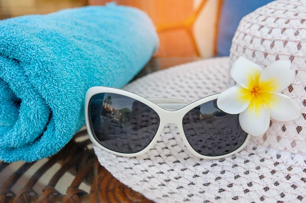 Gafas de sol en el sombrero y flores en la playa — Foto de Stock